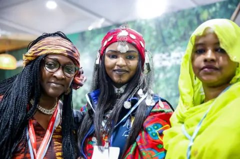 Getty Images Women in traditional dresses pose in Congo Pavilion on the second day of the COP27 UN Climate Change Conference, held by UNFCCC in Sharm El-Sheikh International Convention Center. COP27, running from November 6 to November 18 in Sharm El Sheikh focuses on implementation of measures already agreed during previous COPs. The Conference in Sharm El Sheikh focuses also on the most vulnerable communities as the climate crisis hardens life conditions of those already most disadvantaged.