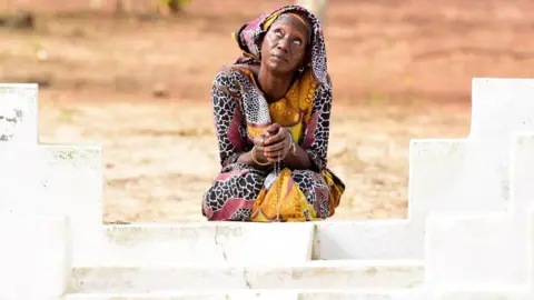 AFP/Getty Images A Senegalese woman prays in front of the grave of a loved one as she marks the 15th anniversary of the sinking of the ship 'Le Joola' on September 26, 2017 in Dakar. Ceremonies marking the 15th anniversary of Senegal's Joola ferry tragedy, in which nearly 1,900 people died are taking place in Dakar