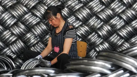 Getty Images A woman works in a steel hub factory in China