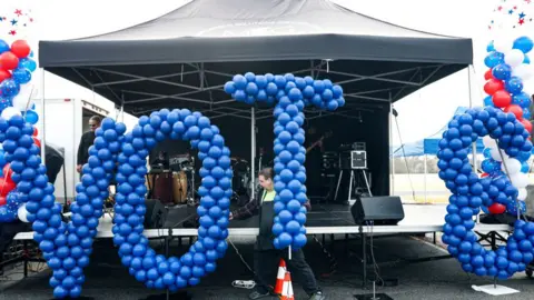 AFP via Getty Images A volunteer sets up a balloon display during a get out the vote rally for Democratic senate candidates Jon Ossoff and Raphael Warnick