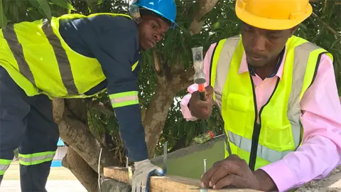 BBC José Joaquim (R) teaching people to make a cyclone-proof roof at a college in Beira, Mozambique