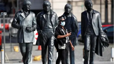 Reuters Beatles statue and woman wearing mask