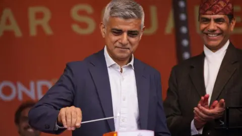 PA Media Sadiq Khan lighting a candle during the Diwali celebration on Trafalgar Square