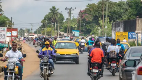 Getty Images Men ride motorcycles through traffic in Ganta Liberia