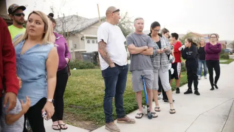 Getty Images Neighbours stand outside a home where a couple was arrested after police discovered that 13 people had been held captive in filthy conditions with some shackled to beds with chains and padlocks, January 15, 2018
