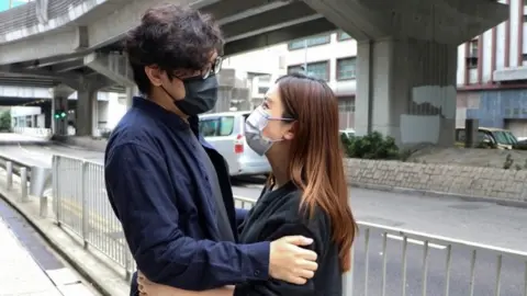 Reuters Pro-democracy activist Sam Cheung hugs his wife as he arrives to report to the police station