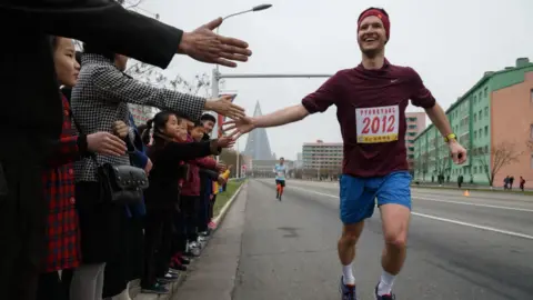 AFP/Getty A foreign runner high-fives North Koreans as he runs the marathon