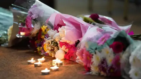 PA Media Flowers and candles left on the floor at a vigil.