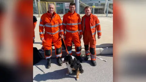 Lincolnshire Fire and Rescue Service Three firefighters with rescue dog