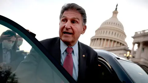 Getty Images Joe Manchin (D-WV) is followed to his car by reporters after participating in a vote at the U.S. Capitol Building on December 14, 2021 in Washington, DC.