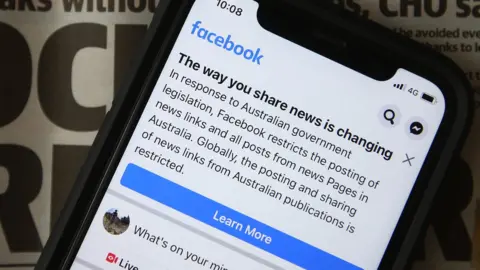 Getty Images A photo shows a phone with a warning message about restrictions on news content in Australia
