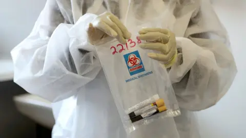 Reuters A health worker holds a Covid-19 sample collection kit of a vaccine in Johannesburg, South Africa