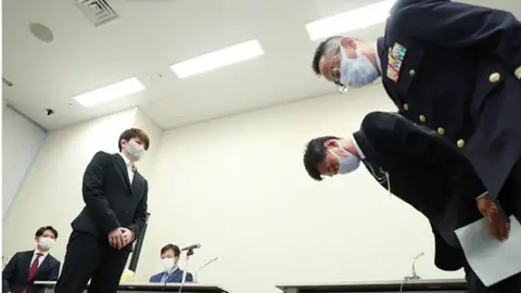 Getty Images Members (R) of Japan's Ministry of Defense and Japan's Ground Self-Defense Force bowing to apologise to Rina Gono