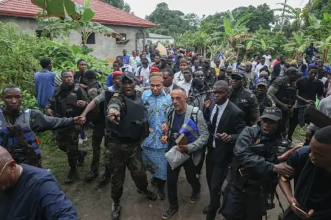 Daniel Beloumou Olomo/AFP Kylian Mbappé surrounded by Cameroonian security forces, family and well-wishers.