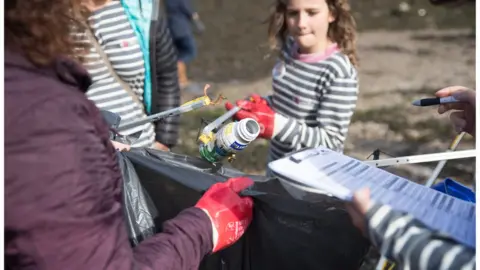 Getty Images Volunteers litter pick waste from the coastline