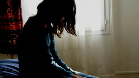 AJ PHOTO/SCIENCE PHOTO LIBRARY Teenage girl sitting on her bed