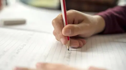Getty Images Boy writing in a notepad doing his school work spelling or homework