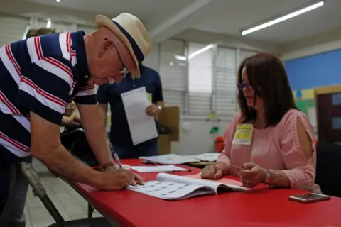 AFP/Getty Images A man signs a voting list before casting his ballot during the referendum for Puerto Rico political status at a polling station in Guaynabo, on 11 June, 2017.