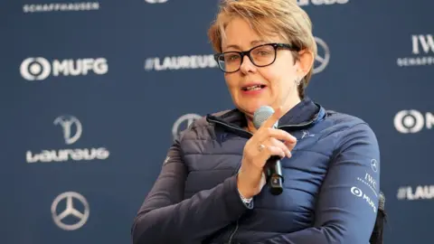 Getty Images Baroness Tanni Grey-Thompson wears black glasses and a blue anorak, and is holding a microphone