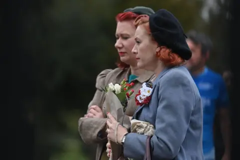 Getty Images Well-wishers carry floral tributes to Britain's Prince Philip, Duke of Edinburgh, the day after his death at the age of 99, outside Windsor Castle in Windsor, west of London on April 10, 2021