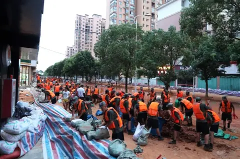 EPA People's Liberation Army (PLA) soldiers build a temporary embankment to contain the flooded Poyang Lake in Lushan city, Jiangxi province, China, 13 July 2020.