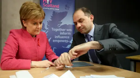 PA First Minister Nicola Sturgeon is given an HIV test by George Valiotis, chief executive of HIV Scotland, at the Scottish Parliament, Edinburgh