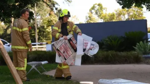 Reuters Fire crews remove evidence in bags marked "asbestos" from South Korea's consulate in Melbourne