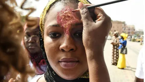 Getty Images woman paints another woman's face to look like an injury - Saturday 25 May 2019
