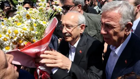 Getty Images Kemal Kilicdaroglu receives flowers from a well-wisher after casting his vote at a polling station in Ankara