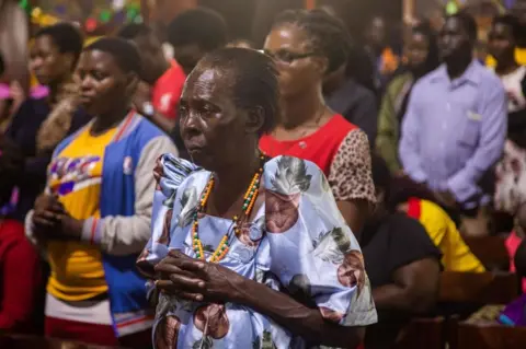 AFP Catholic faithful gather inside the Basilica of the Uganda Martyrs to pray after receiving news about the death of former Pope Emeritus Benedict XVI in Namugongo, Kampala, Uganda, on December 31, 2022