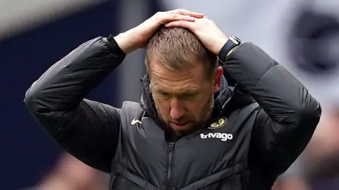 Chelsea boss Graham Potter with his head in his hands on the touchline