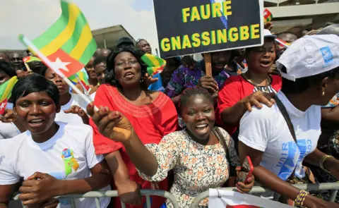 EPA Smiling people waving the Togolese flag at the airport in Abidjan, Ivory Coast - Monday 28 January 2019