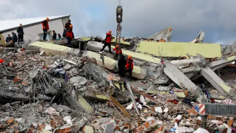 Reuters Rescue workers on a pile of rubble