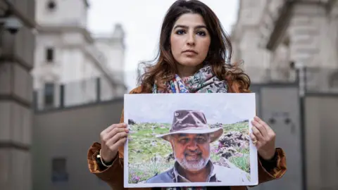 Getty Images Roxanne Tahbaz holds a photograph of her father, Morad Tahbaz, outside the Foreign, Commonwealth and Development Office