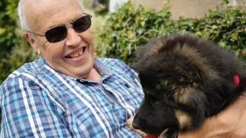 Family photo Bernard Lawrence pictured laughing with a pet dog