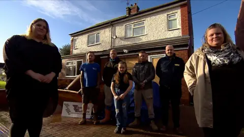 A group of people standing outside a house