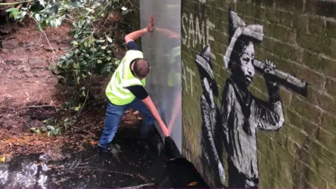 Shaun Whitmore/BBC Perspex barrier put up over a Banksy piece in Oulton Broad.