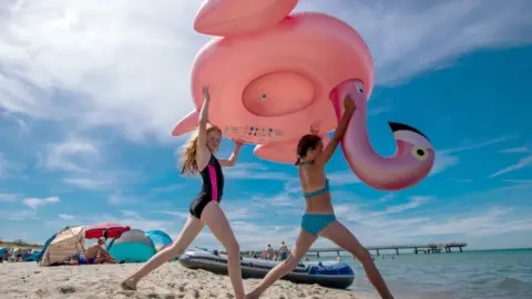 AFP Two girls carry an inflated flaming at the beach of Rerik at the Baltic Sea, northeastern German