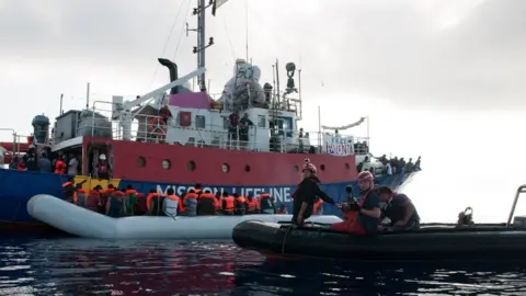 AFP Migrants on an inflatable boat boarding the Lifeline sea rescue boat at sea on June 21, 2018