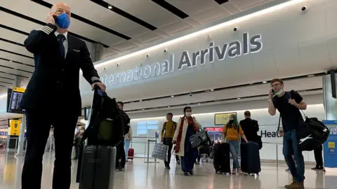 Reuters A member of aircrew is seen wearing a protective face mask at Heathrow Airport