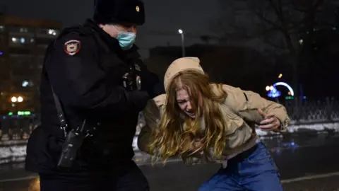 Reuters A law enforcement officer detains a woman who is bent over at Moscow protest