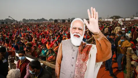 Getty Images Women from various districts are seen near cut-outs of India's Prime Minister Narendra Modi at a rally held by Modi on December 21, 2021 in Allahabad, India.