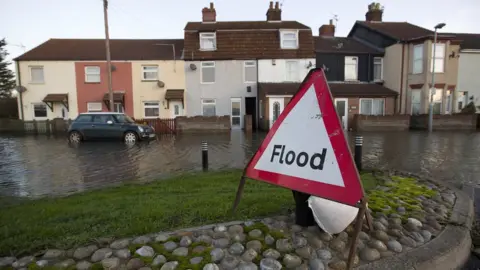 Getty Images A flood warning sign displayed on a street where flood waters rose to the front doors of houses, in Great Yarmouth on 6 December 2013