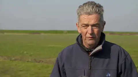 Jonny Michel/BBC Guy Smith farmer from St Osyth in Essex standing in a field talking about fertiliser prices rising because of war in Ukraine