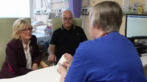 Lisa and Mike sat at a desk talking to nurse Cynthia