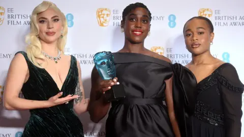 EPA Lady Gaga (L) and last year's winner Bukky Bakray (R) present the rising star prize to Lashana Lynch