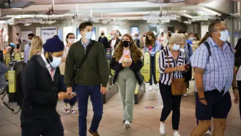 Reuters Commuters wearing masks at a London Underground station