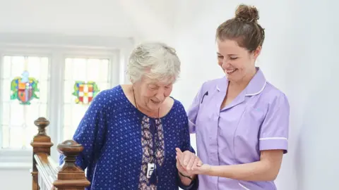 Care worker helping elderly woman down some stairs