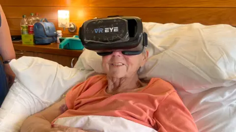 St Giles Hospice Woman in bed wearing VR goggles