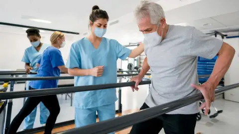 Getty Images man walking with support at rehab centre